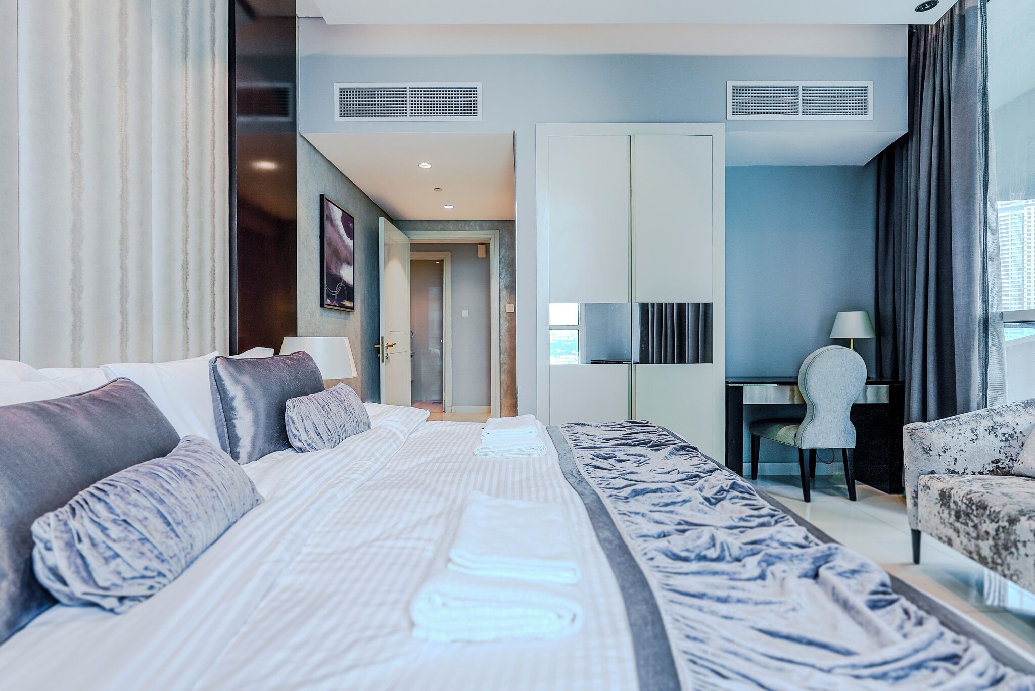 A modern hotel room with a large bed, a desk, and a chair.