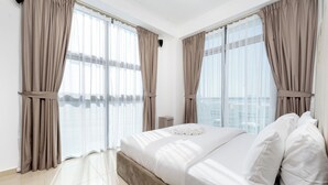 Ein modernes Hotelzimmer mit einem großen Bett, beigen Vorhängen und Blick auf die Stadt.
