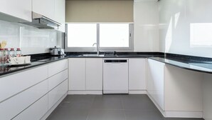 Eine moderne Küche mit weißen Schränken, einer schwarzen Arbeitsplatte und einem Fenster über der Spüle.