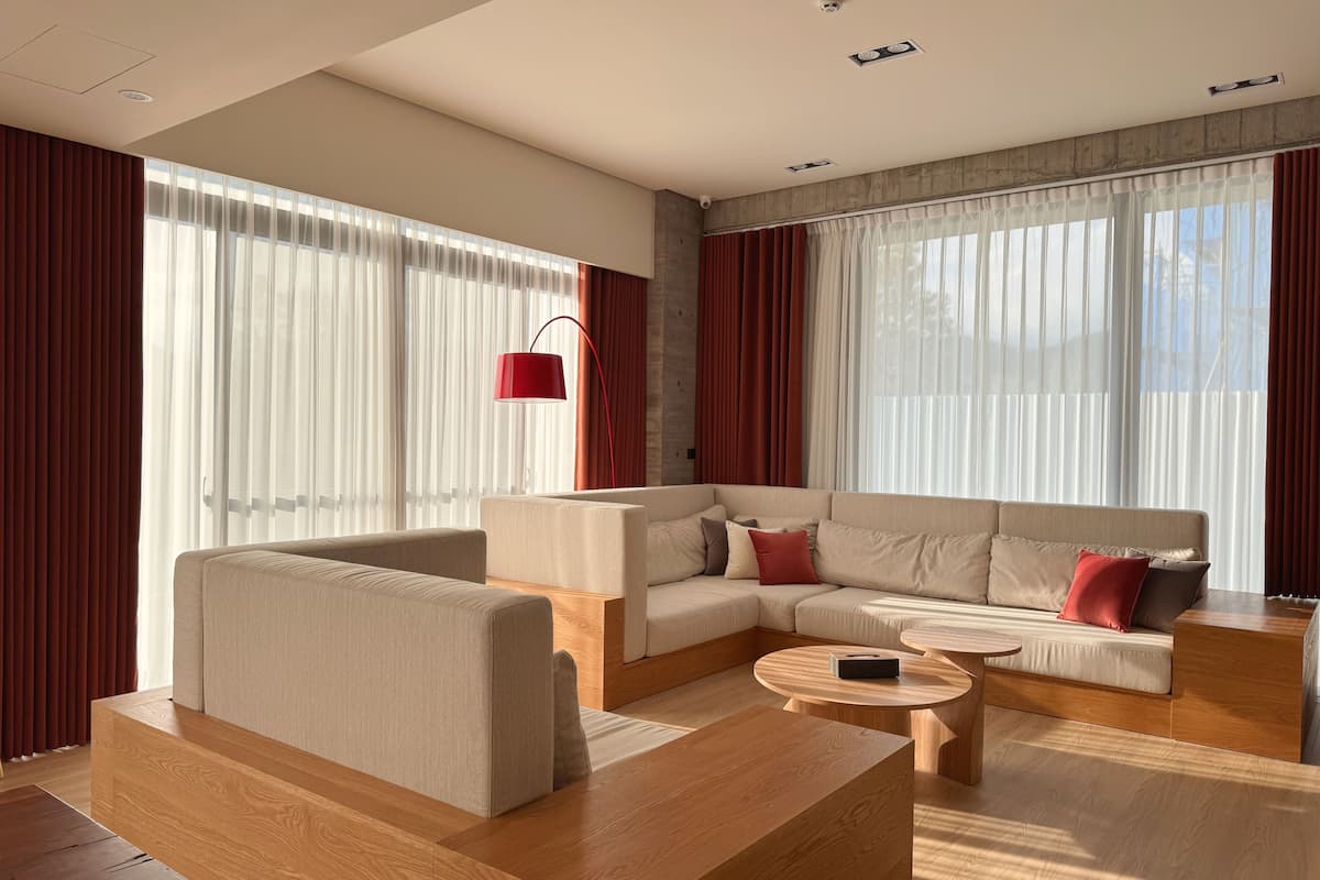 A modern living room with a sectional sofa, a wooden coffee table, and a red floor lamp.