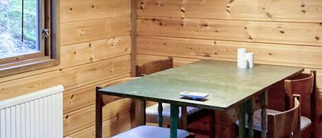 A wooden interior with a table and chairs, a window, and a radiator.
