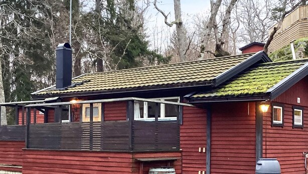 A red wooden cabin with a tiled roof, a chimney, and a barrel. - 4 Person Holiday Home in Djurhamn (Djurhamn)