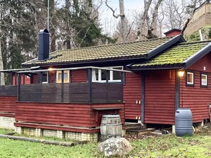 A red wooden cabin with a tiled roof, a chimney, and a barrel. - 4 Person Holiday Home in Djurhamn (Djurhamn)