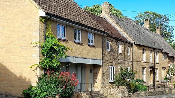 A row of traditional stone houses with a central building featuring a large window and a door. - Greenham Rise (Stoke-sub-Hamdon)