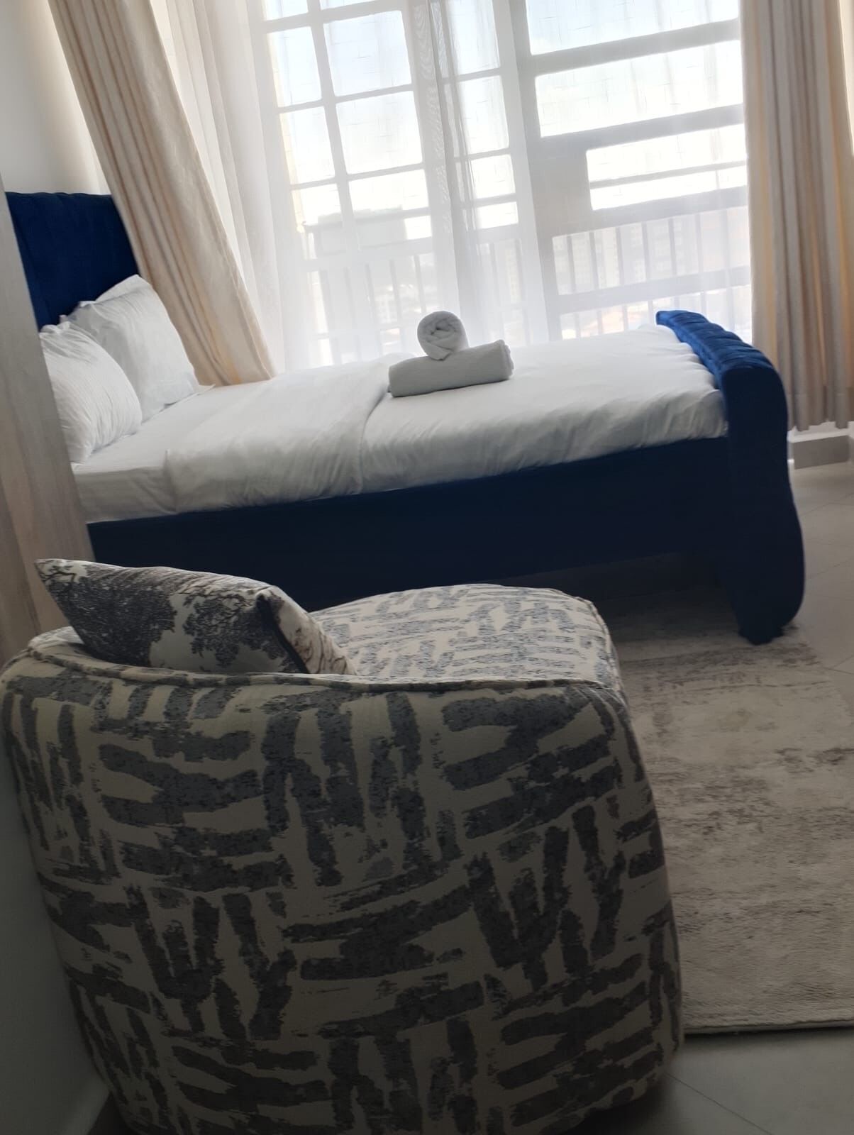 A bedroom with a bed, a pillow, a bedside table, and a window with curtains.