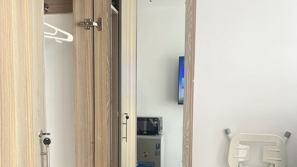 Une armoire en bois avec un miroir, un four à micro-ondes et une petite table avec une chaise.