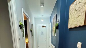 A hallway with a blue accent wall, a white door, and two rugs on the floor. - Spacious Apartment - With Parking - Town Centre Location - Walk to Beach! (Bournemouth)