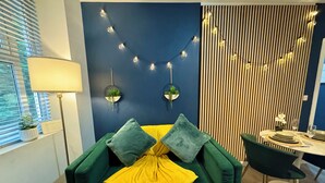 A modern living room with a green sofa, yellow throw, and decorative lights. - Spacious Apartment - With Parking - Town Centre Location - Walk to Beach! (Bournemouth)