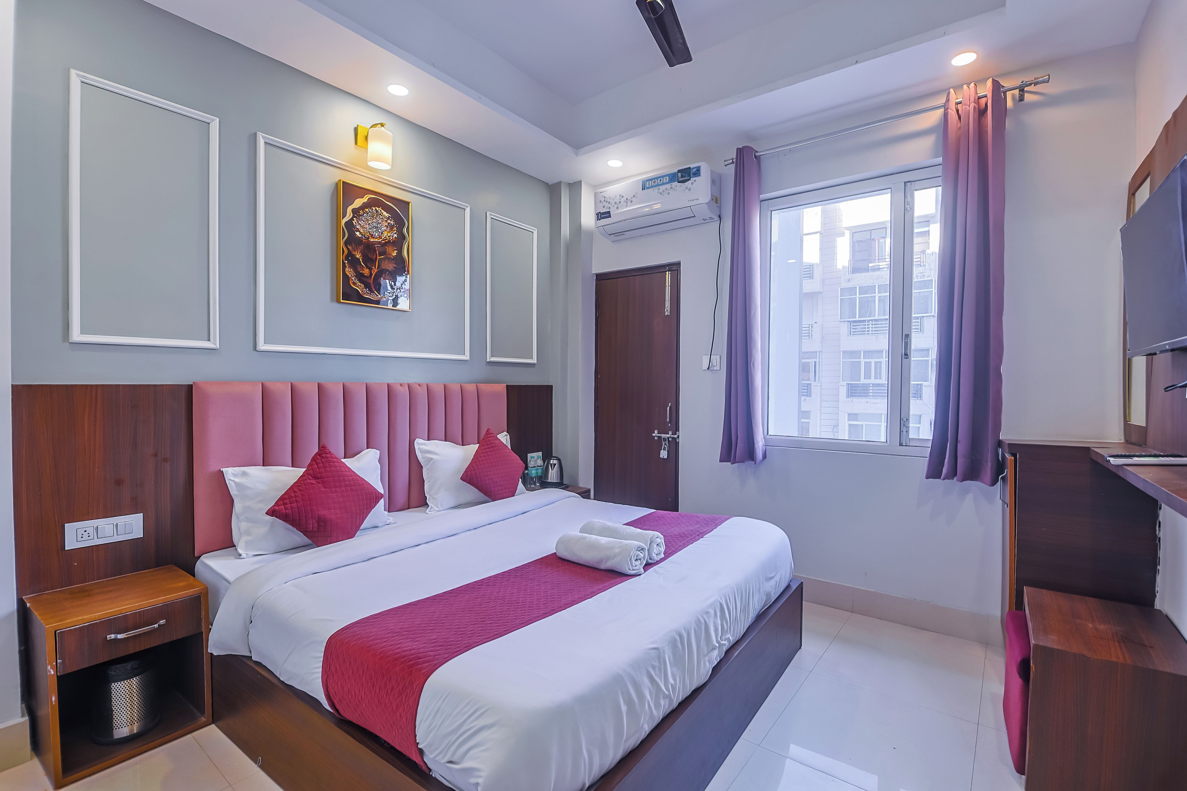 Habitación de hotel con una cama grande, una mesita de noche, un armario, una ventana con cortinas y un equipo de aire acondicionado de pared.