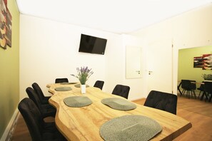 A dining area with a long wooden table, black chairs, and a white vase with purple flowers. - BIG New 6Rms Boutique Flat City Center, KaDeWe, ZOO, Messe, 1A Location (Berlin)