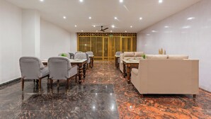 A modern dining area with a marble floor, a sofa, and a dining table with chairs. - Treebo Sloka Residency (Ranchi)