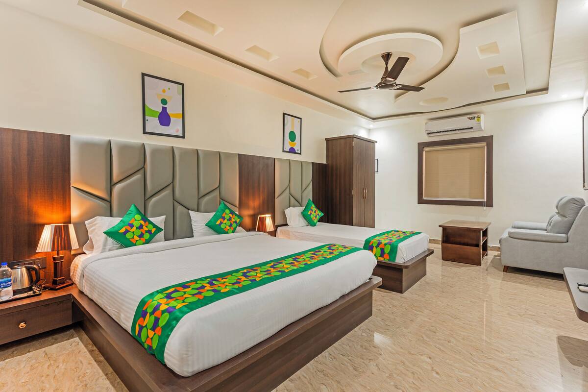 A hotel room with a large bed, a sofa, a desk, and a ceiling fan.