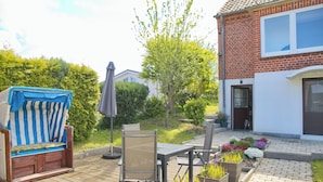 A patio with a wooden deck, a striped chair, a table, and a chair. - Spacious, allergy-friendly accommodation in the basement near the beach and town (Grömitz)