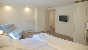A bedroom with a bed, a chair, a TV, and a wardrobe. - Spacious, allergy-friendly accommodation in the basement near the beach and town (Grömitz)