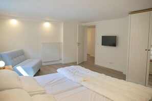 Ein Schlafzimmer mit Bett, Stuhl, Fernseher und Kleiderschrank.