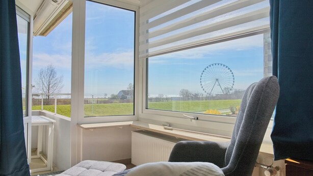 A room with a large window, a chair, a small table, and a radiator. - Comfortable Apartment Hanseat II App. 121 with sea view and balcony in Grömitz (Grömitz)