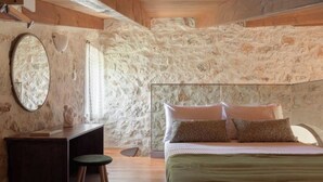 Ein Schlafzimmer mit Steinwand, einem Bett mit Kissen, einem Nachttisch und einem Spiegel.