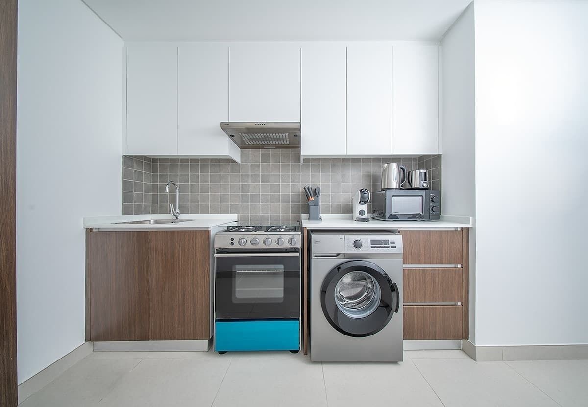 A modern kitchen with a built-in oven, microwave, and washing machine.
