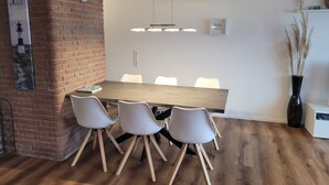 A modern meeting room with a wooden table, white chairs, a clock, and a wall-mounted air conditioning unit. - Comfortable vacation apartment Seeadler 30 with balcony near Friesenstrand in Tossens (Butjadingen-Tossens)
