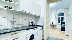 Ett modernt kök med vita skåp, en inbyggd tvättmaskin och en kakelbeklädd vägg bakom arbetsbänken.
