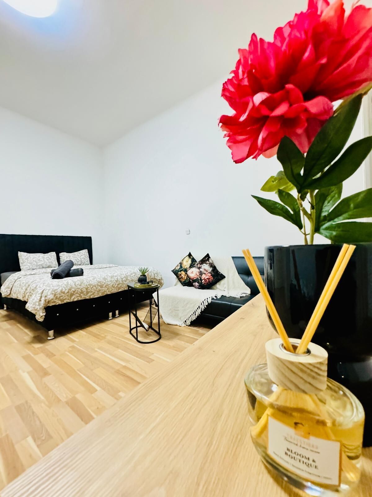 A modern bedroom with a bed, bedside table, and a large potted plant.