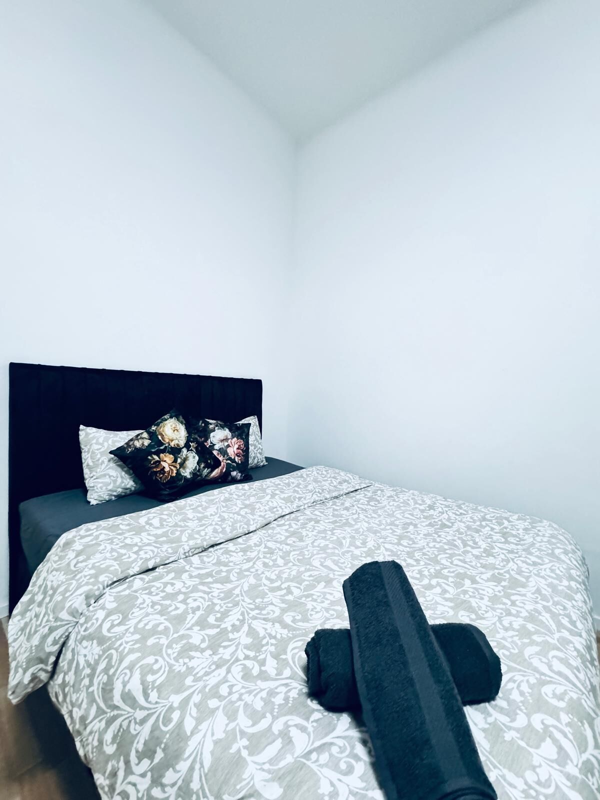 Une chambre à coucher avec un lit, des oreillers et une serviette enroulée.
