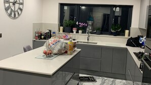 Une cuisine moderne avec un sol en marbre, une grande horloge et une fenêtre ornée de plantes.