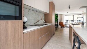 Eine moderne Küche mit eingebautem Backofen, Marmorfliesenspiegel und Holzschränken.