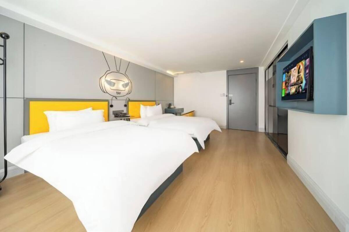 A modern hotel room with a large bed, a TV mounted on the wall, and a unique ceiling light fixture.