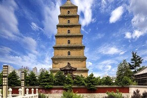 A multi-tiered pagoda-like structure with traditional architectural elements, surrounded by greenery and urban buildings. - IU Hotel (Xi'an Zhonggulou Square) (Xi'an)