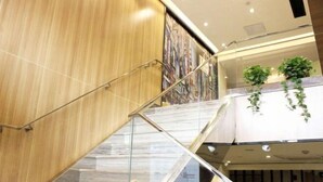 A modern interior with a glass staircase, wooden paneling, and a mural on the wall. - IU Hotel (Xi'an Zhonggulou Square) (Xi'an)
