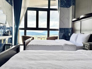 A hotel room with two beds, a dining table, and a view of mountains through large windows. - Sun Heaven Dalat (Cam Ly - Da Lat)