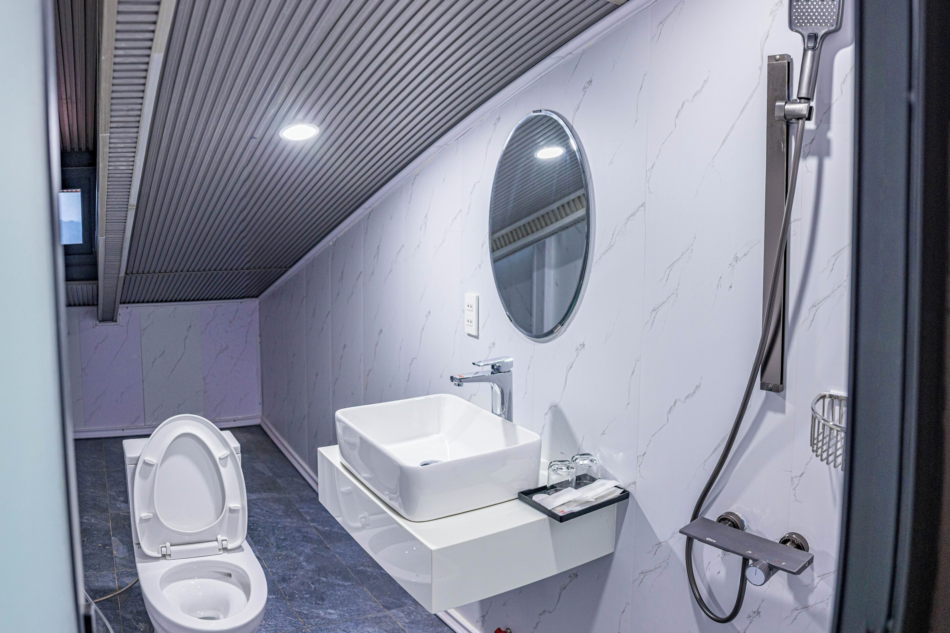 Een moderne badkamer met een wit wastafelmeubel, spiegel en douche.