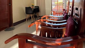 Una habitación con escalera de madera, zona de comedor con sillas, mesa con planta y vista por una ventana.
