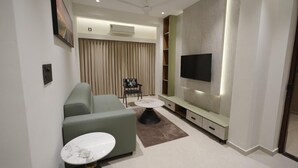 Ein modernes Wohnzimmer mit einer Couch, einem Couchtisch, einem an der Wand befestigten Fernseher und einem Deckenventilator.
