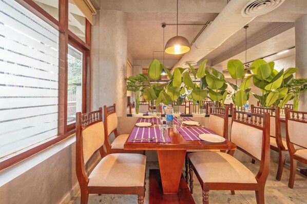 A dining area with a wooden table, chairs, and potted plants.