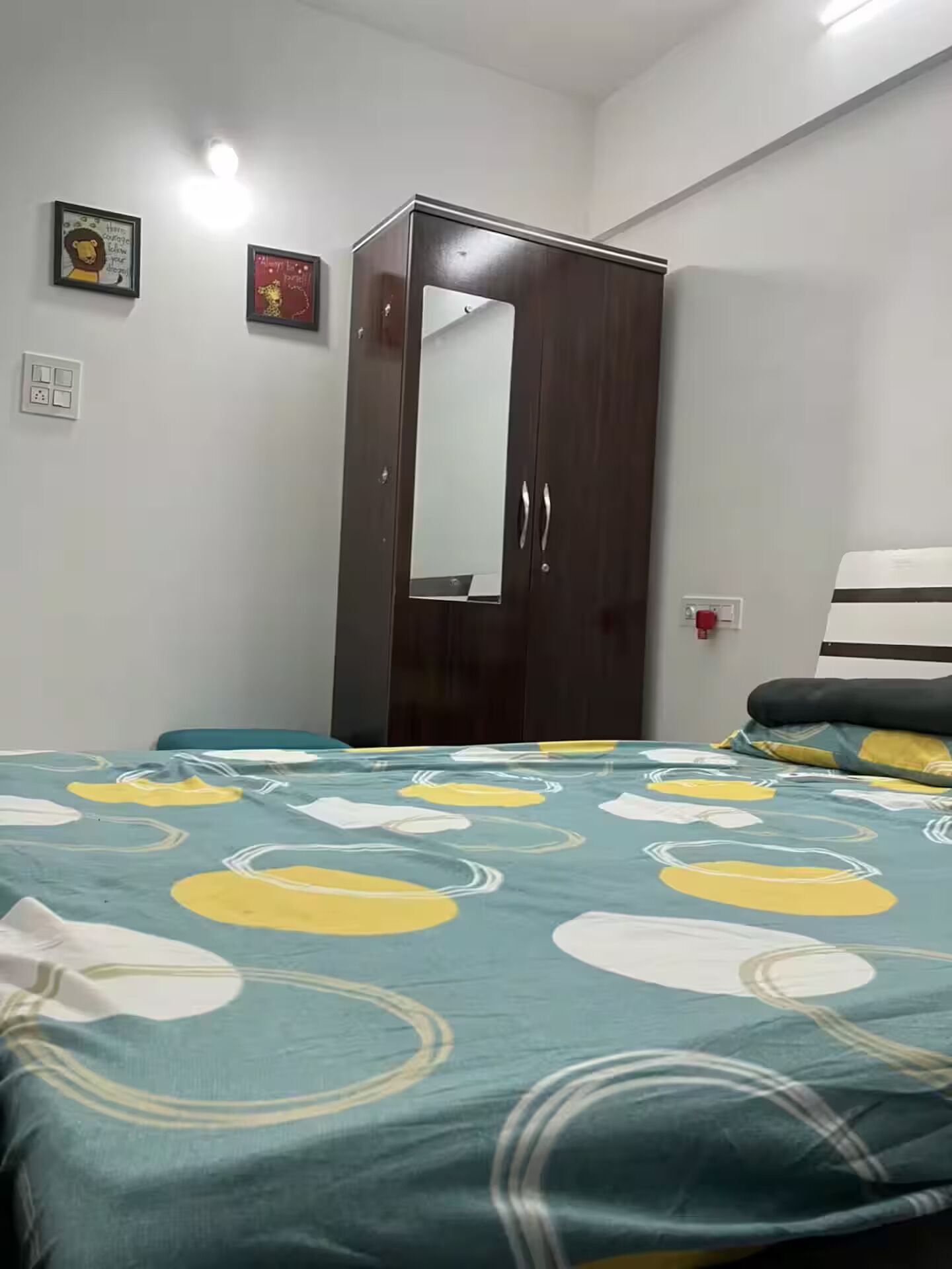 A bedroom with a bed, a wardrobe, and a mirror.
