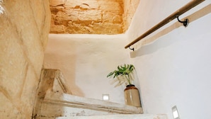 A staircase with a rustic stone wall, a metal handrail, and a potted plant. - Historic 300 Years Townhouse in Birgu, Vittoriosa (Birgu)