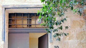 A stone building with a number 20 on the wall, a metal door with a knocker, and a small table with a chair inside. - Historic 300 Years Townhouse in Birgu, Vittoriosa (Birgu)