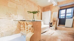A room with a stone wall, a white sofa, a white cabinet, and a small table with a plant. - Historic 300 Years Townhouse in Birgu, Vittoriosa (Birgu)