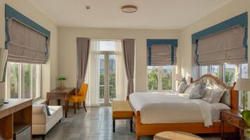 A hotel room with a bed, bedside table, chair, desk, and a view of the outside.