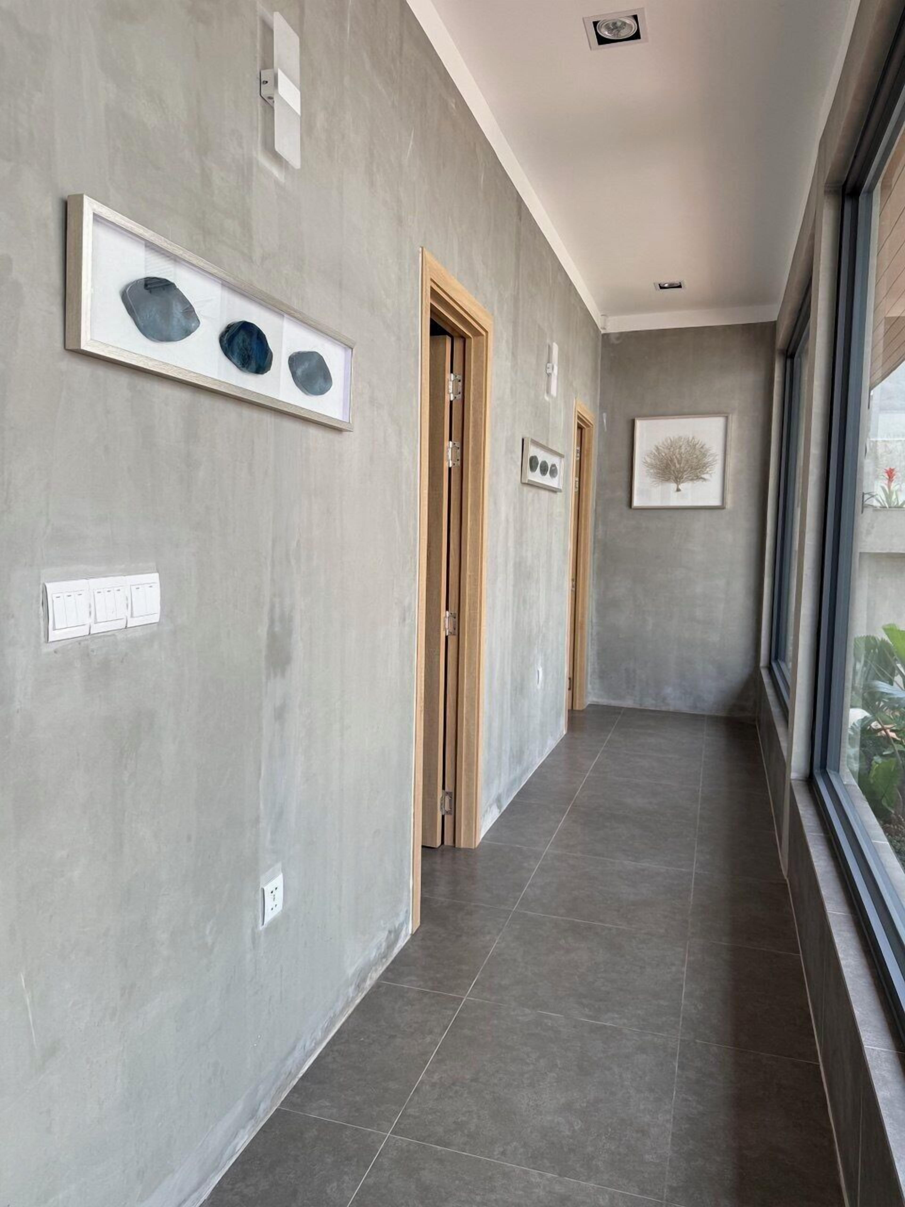 A hallway with grey walls, framed artwork, and a wooden door.