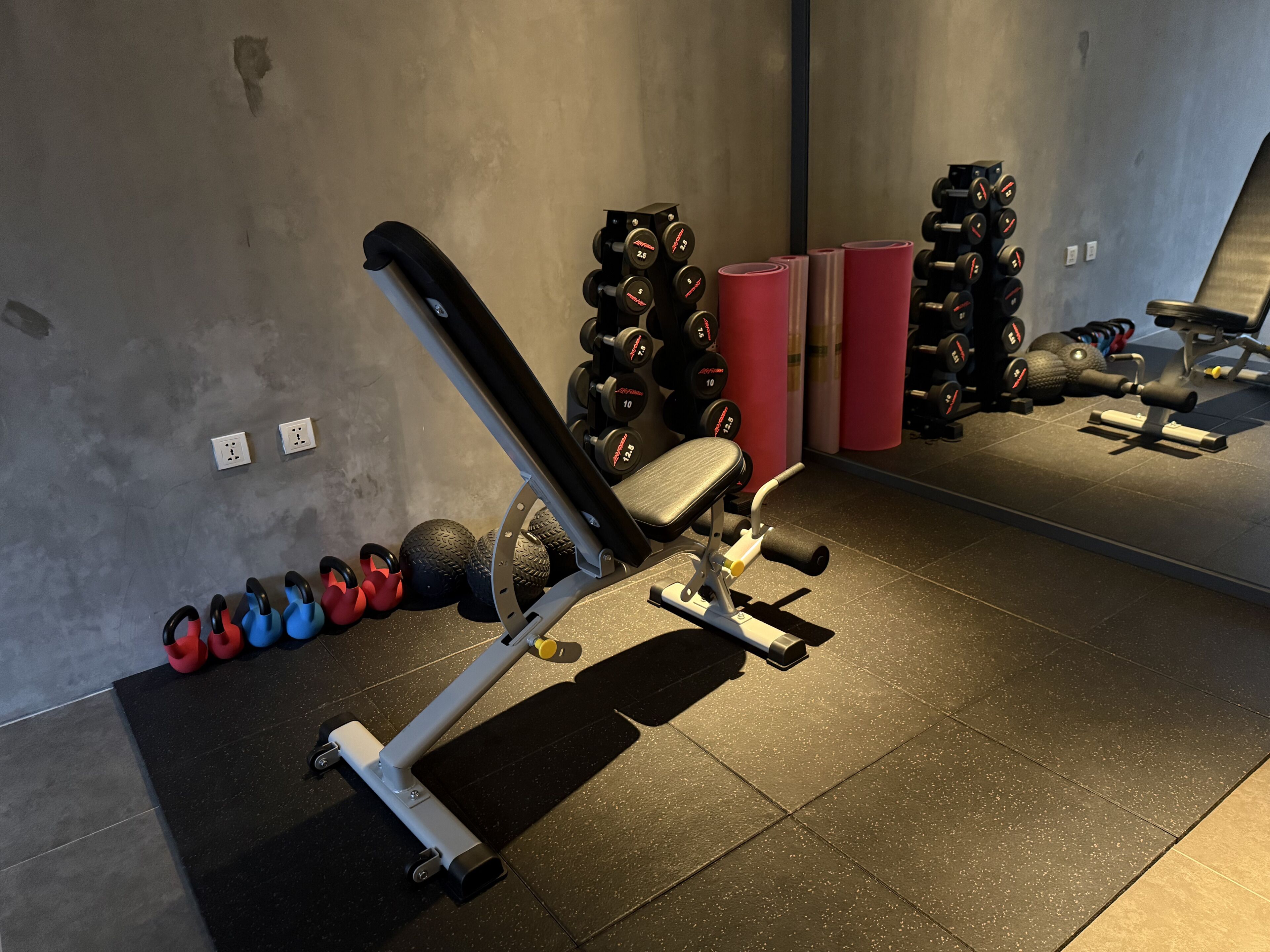 Ein Fitnessraum mit Trainingsgeräten, Gewichte-Stapeln und einer Hantelbank.