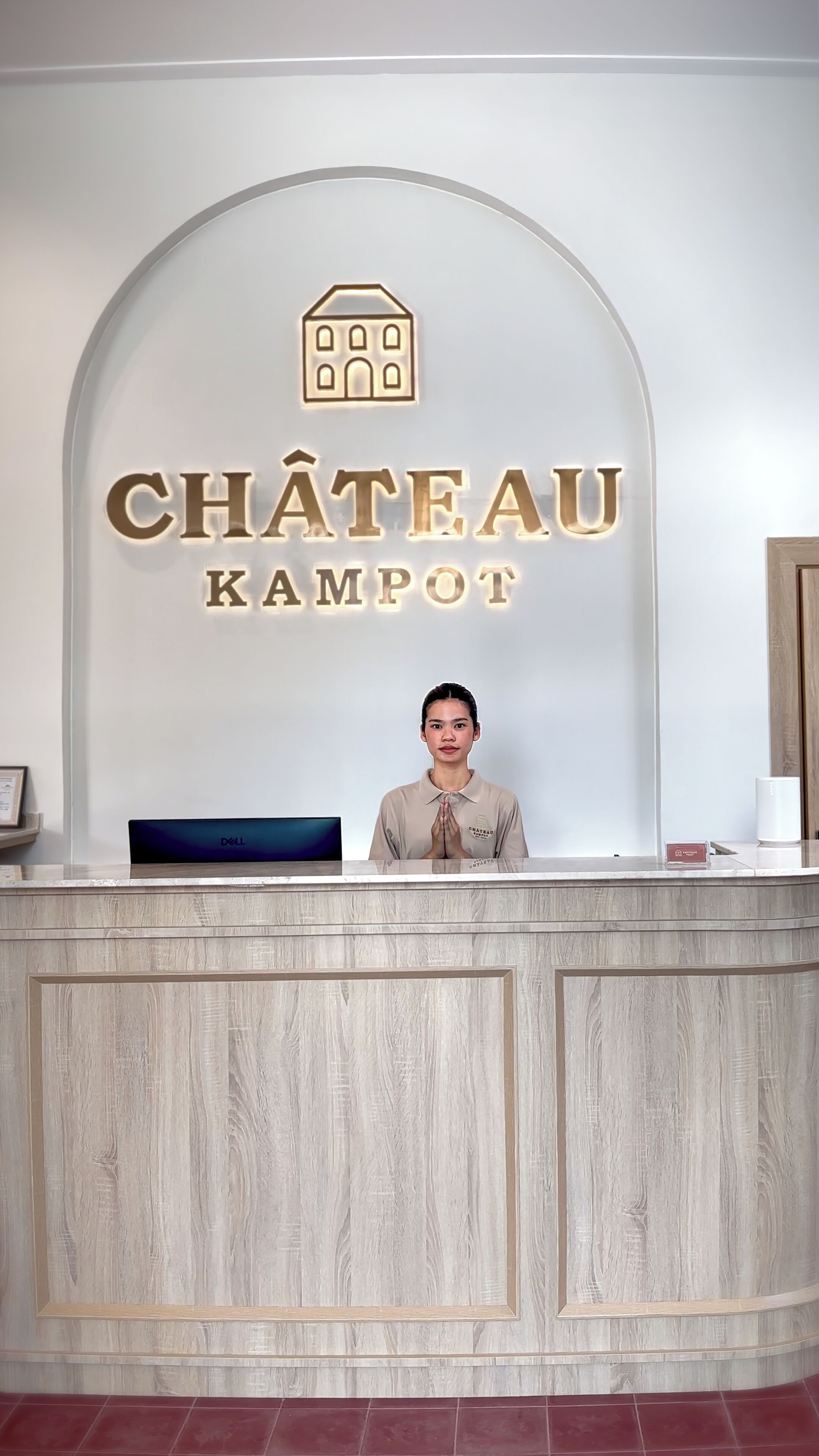 Un mostrador de recepción con un letrero que dice "CHÂTEAU KAMPOT" y un logotipo encima.