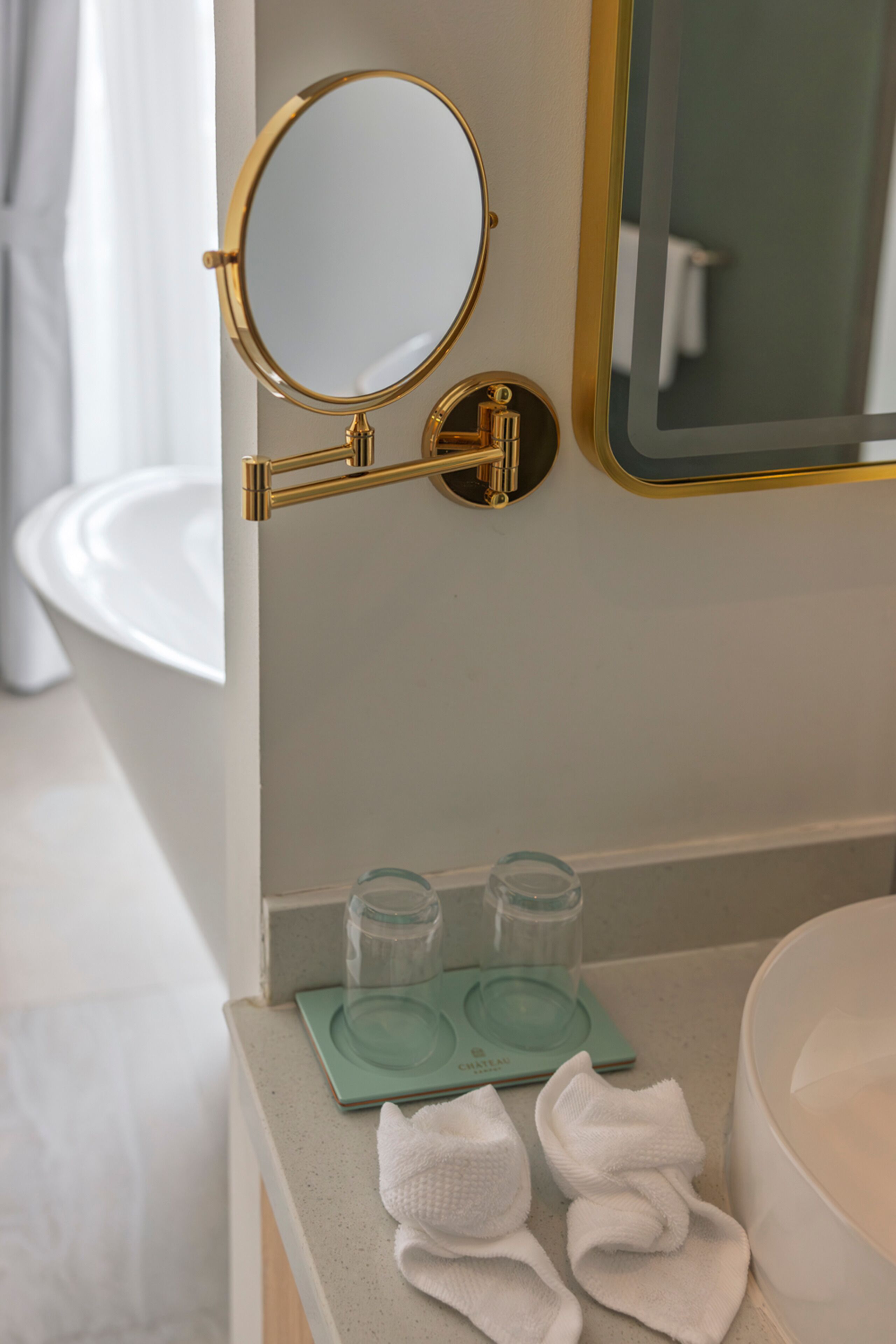 A bathroom with a gold-framed mirror, a white sink, and a green soap dish.