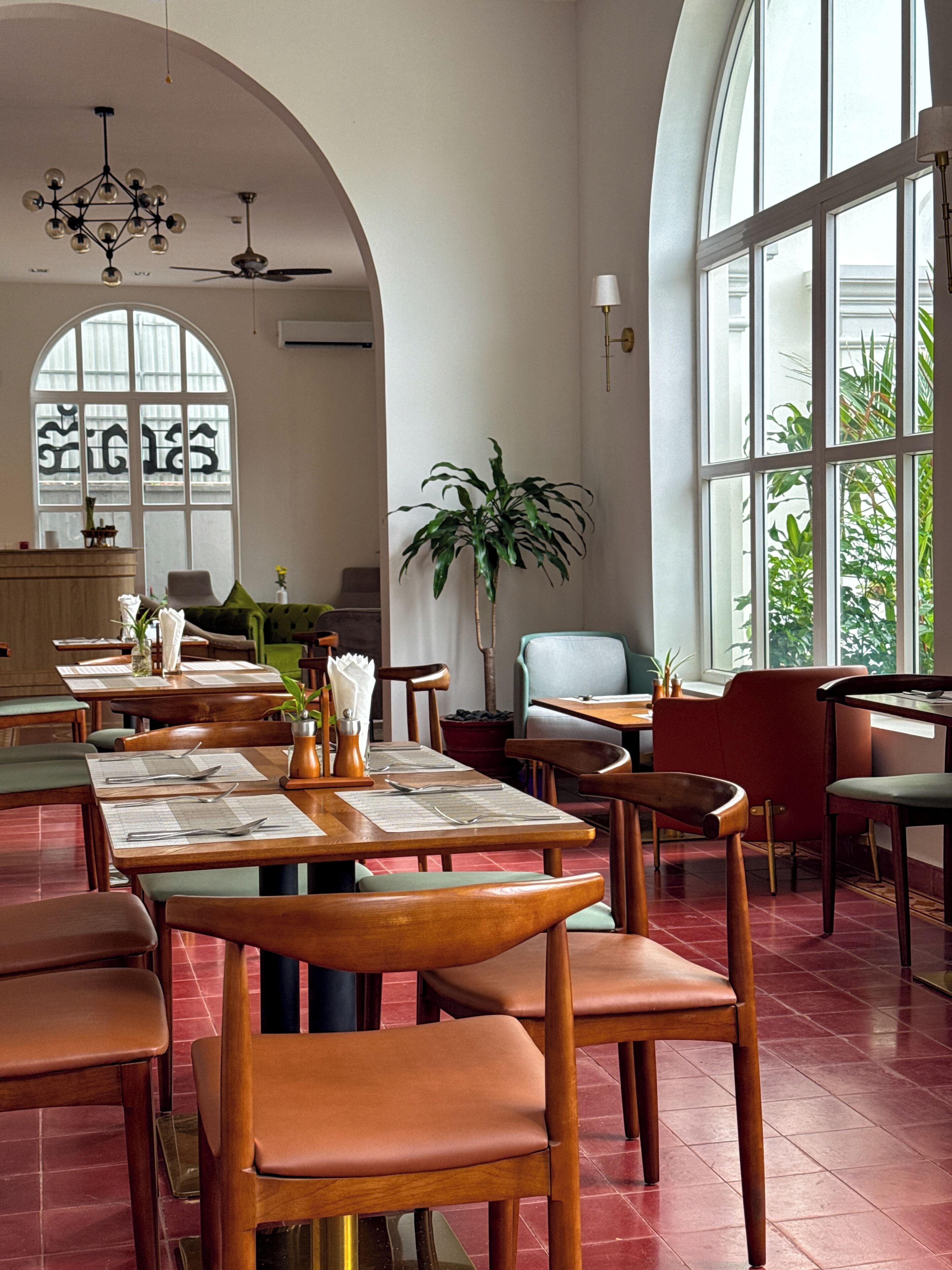 A restaurant with high arched ceilings, large windows, and wooden furniture.