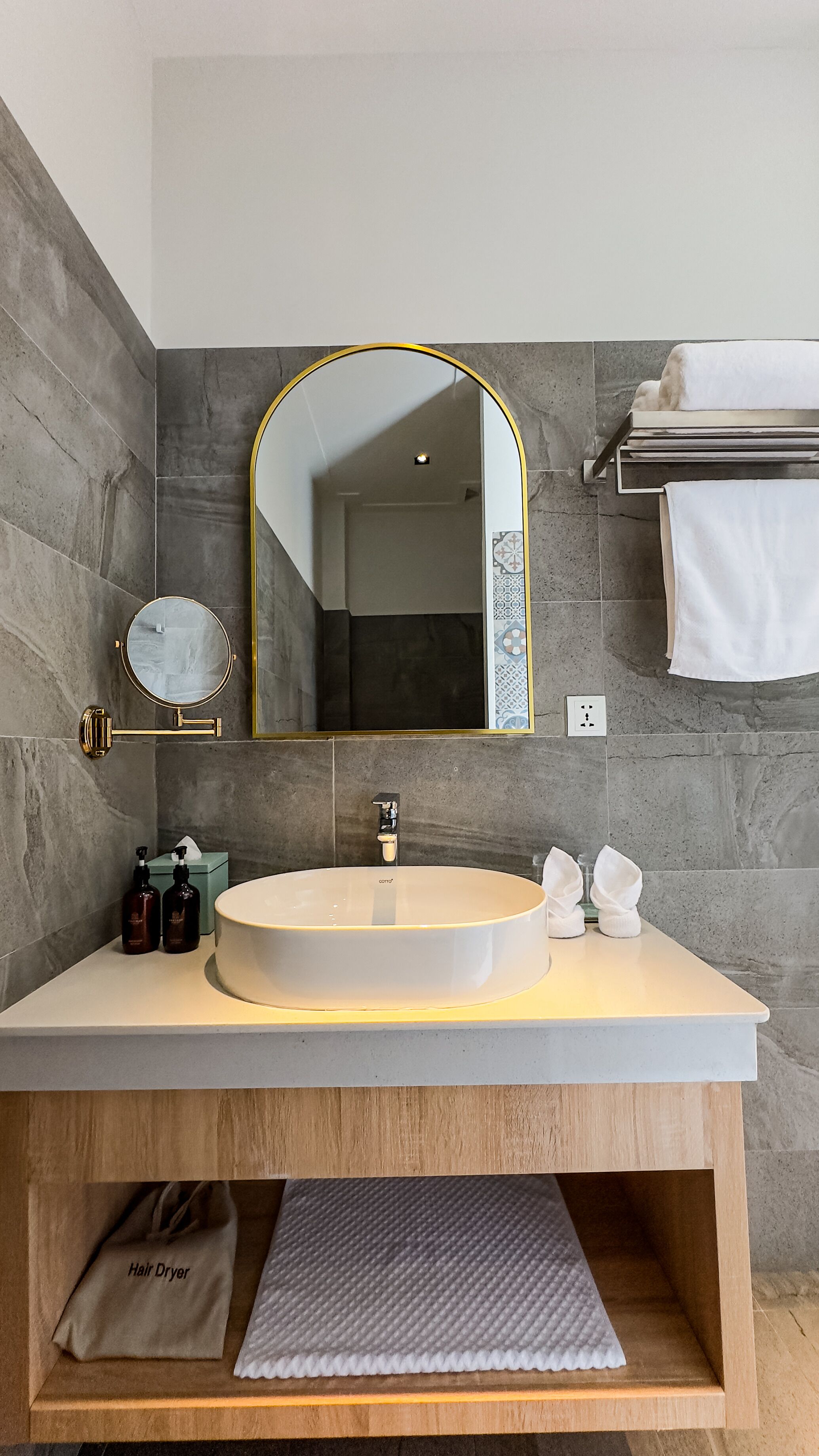 Un baño moderno con un lavabo redondo, un espejo grande y un perchero para toallas.