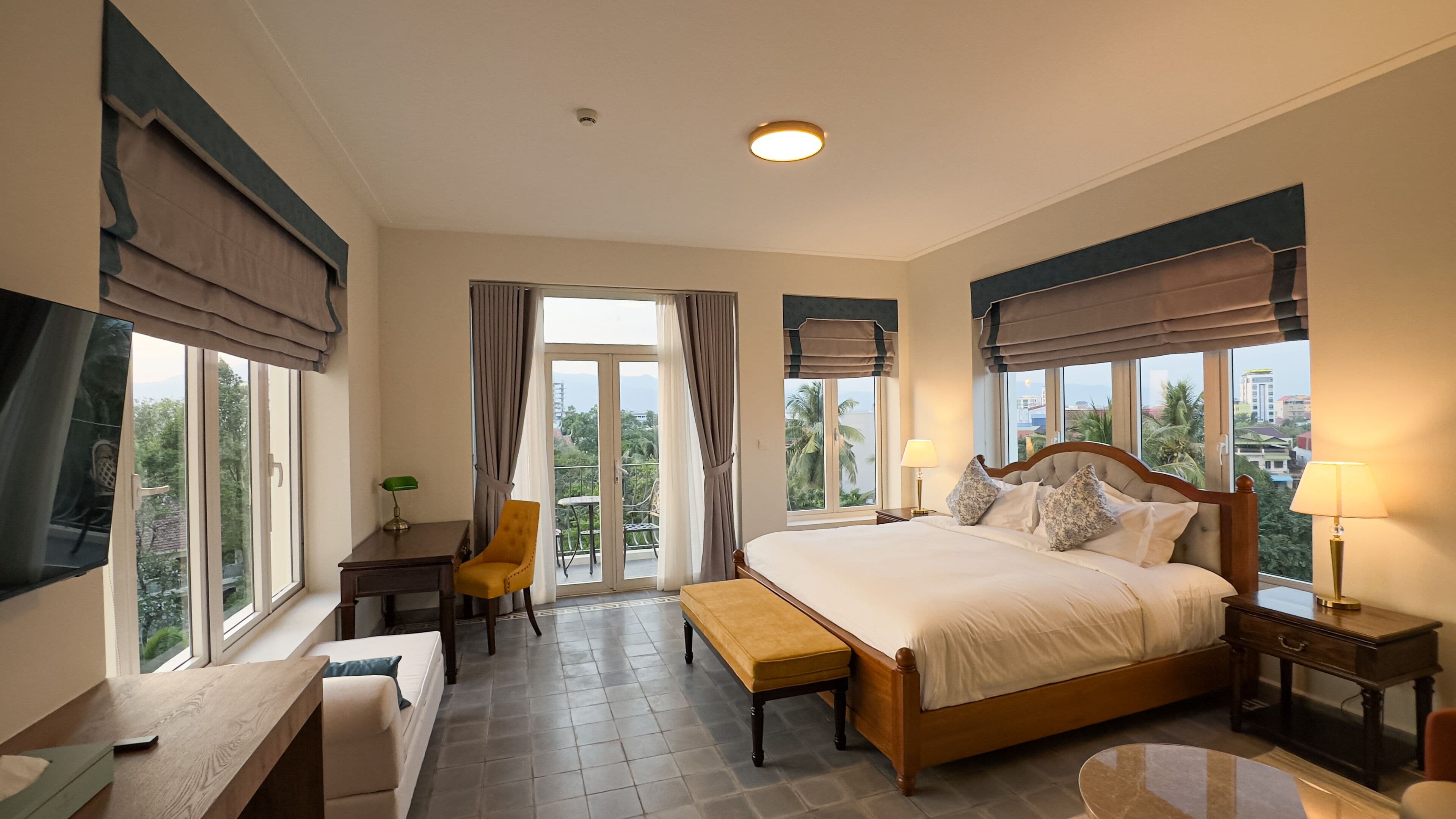 Habitación de hotel con una cama grande, un escritorio, una silla y vistas al exterior.