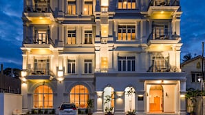 Een meerlaags hotel met een klassieke architectuur, met balkons, grote ramen en een goed verlichte entree.