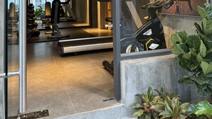 Een moderne sportschool met trainingsapparatuur, een loopband en een groot raam met uitzicht op een zonsondergang.